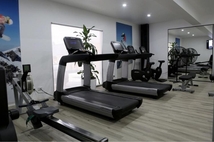 The spin room at CountryFit Gym in Mudgee is lively and energetic, featuring a group of participants engaged in a cycling class. Bright screens display workout metrics, while the vibrant decor adds to the motivating atmosphere.