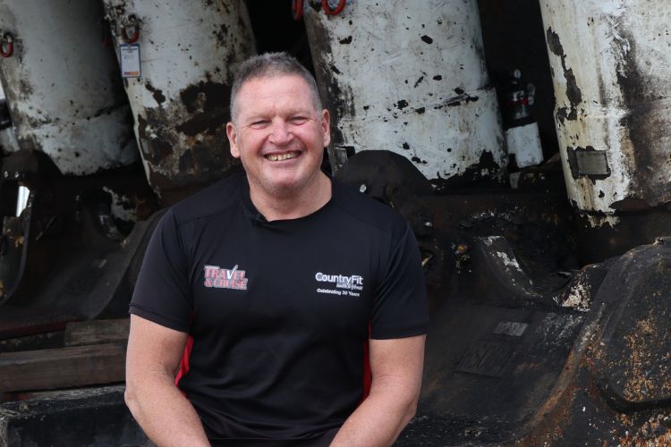 Glenn, the owner of CountryFit Gym in Mudgee, smiles warmly. He is wearing a black CountryFit t-shirt.