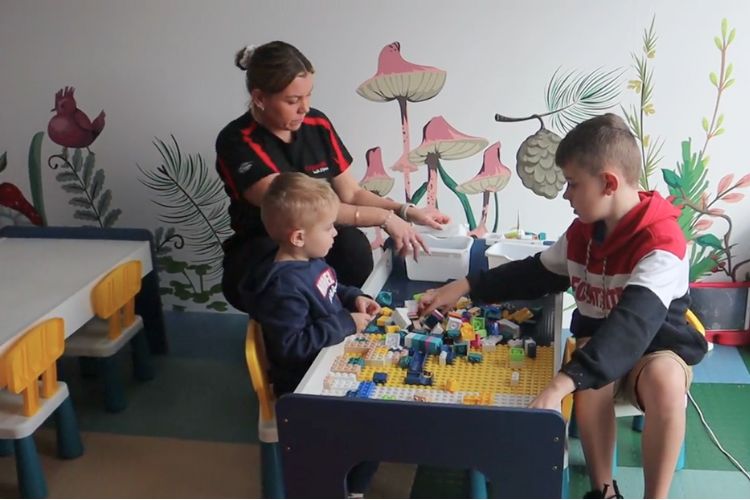 CountryFit Gym in Mudgee creche scene showing a female attendant interacting with two young boys engaged in play with colourful building blocks.